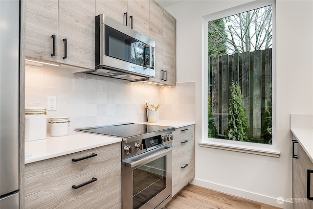 kitchen featuring decorative backsplash, light hardwood / wood-style floors, and appliances with stainless steel finishes