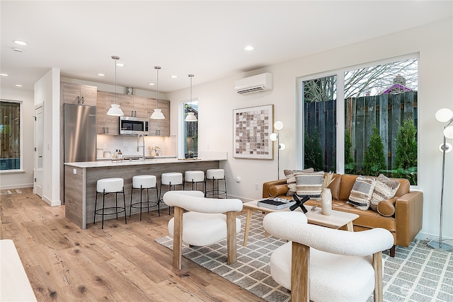 living room with sink, a wall mounted air conditioner, and light wood-type flooring