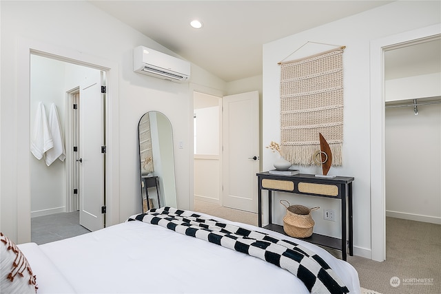 carpeted bedroom with a wall unit AC, a walk in closet, a closet, and vaulted ceiling