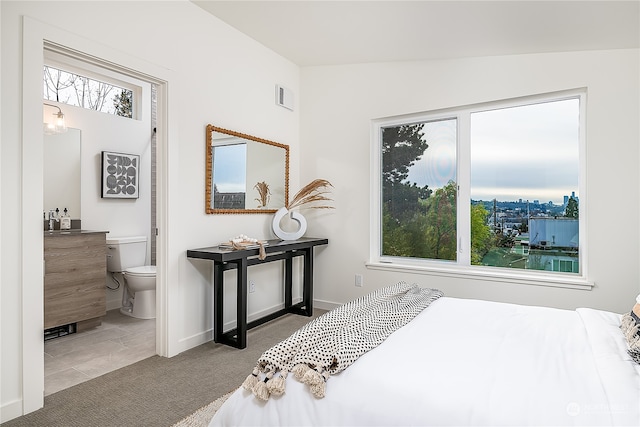 carpeted bedroom featuring ensuite bathroom, multiple windows, and lofted ceiling