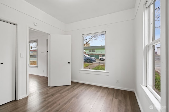 unfurnished room featuring a healthy amount of sunlight and dark hardwood / wood-style flooring