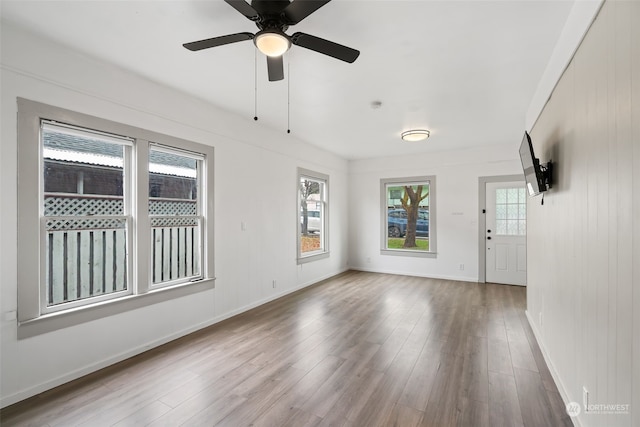 empty room with ceiling fan, light wood-type flooring, and a wealth of natural light