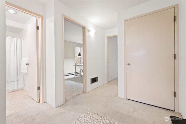 hall with light carpet and a baseboard heating unit