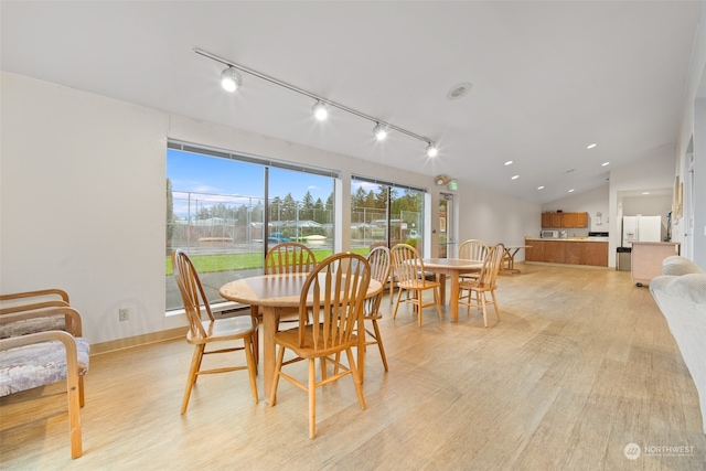 dining room featuring light wood-type flooring, rail lighting, and lofted ceiling