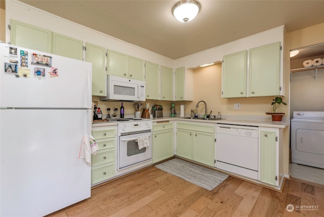 kitchen featuring white appliances, green cabinets, sink, light hardwood / wood-style floors, and washer / clothes dryer