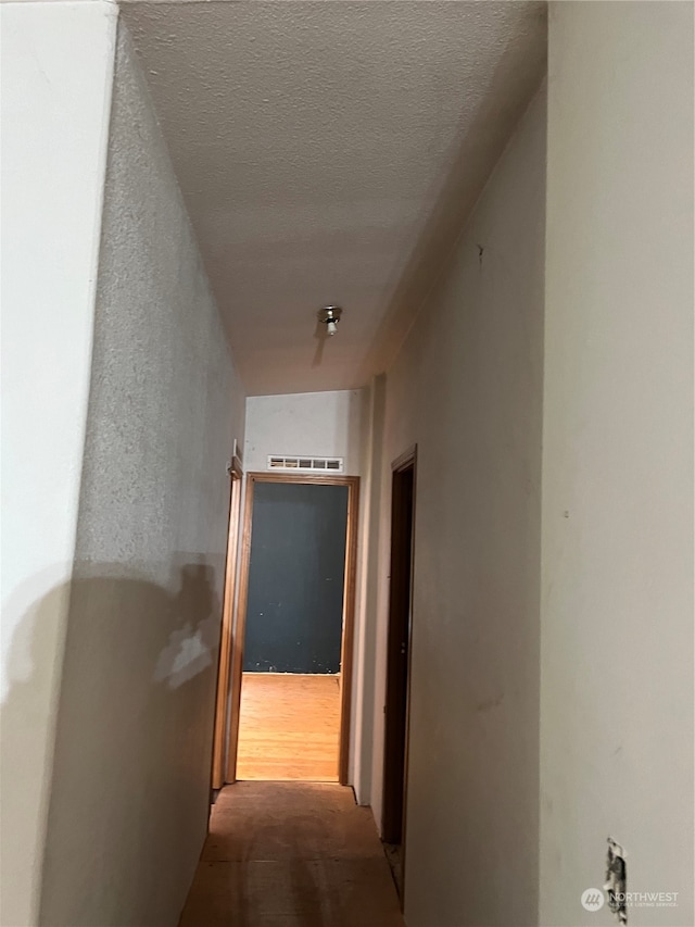 corridor featuring a textured ceiling and light hardwood / wood-style floors