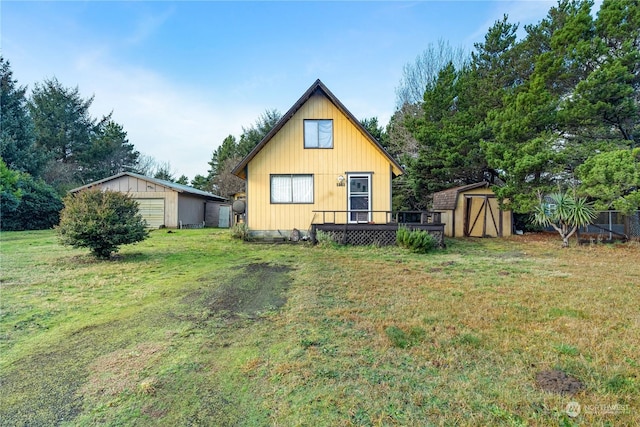 rear view of property with a lawn, a wooden deck, and a storage unit