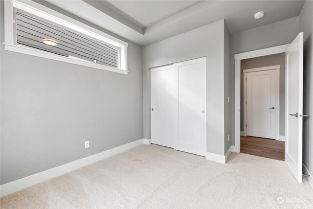 unfurnished bedroom with light colored carpet and a closet