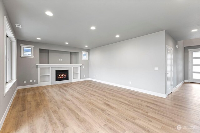 unfurnished living room with plenty of natural light and light hardwood / wood-style floors