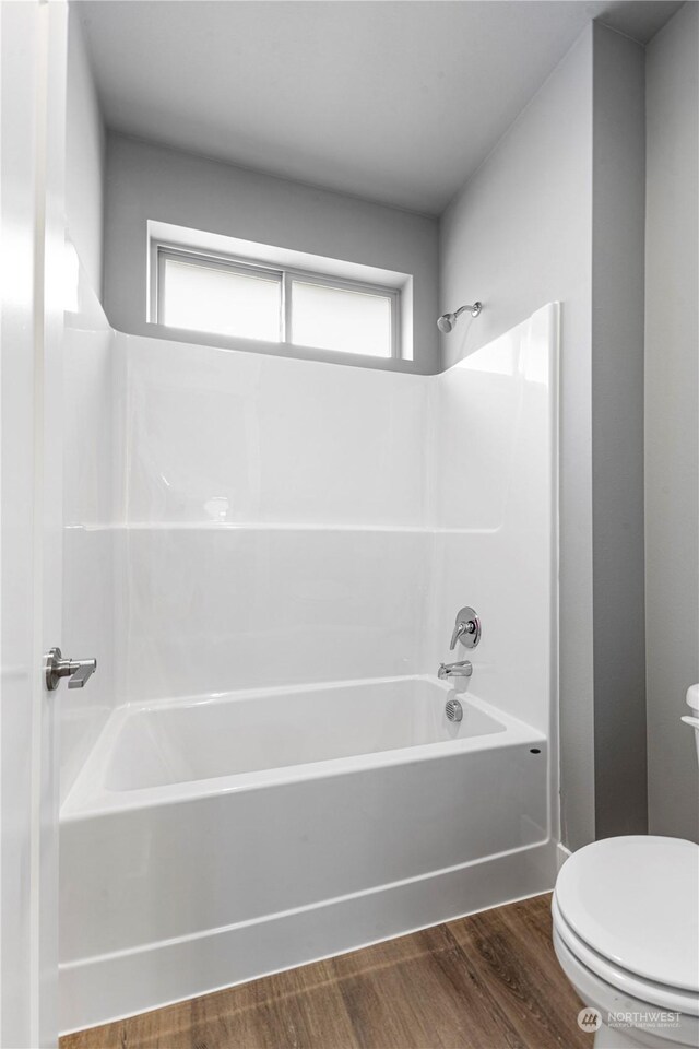 bathroom featuring toilet, wood-type flooring, and shower / washtub combination