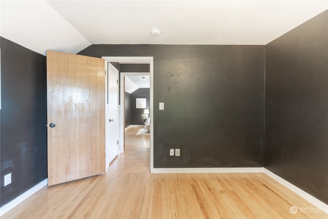 spare room with vaulted ceiling and light hardwood / wood-style flooring