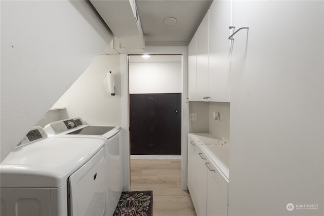 laundry room with washer and clothes dryer, cabinets, and light hardwood / wood-style flooring