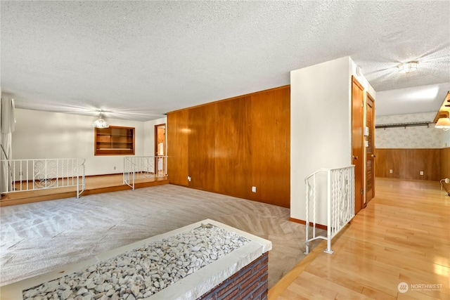 unfurnished room featuring a textured ceiling and wooden walls