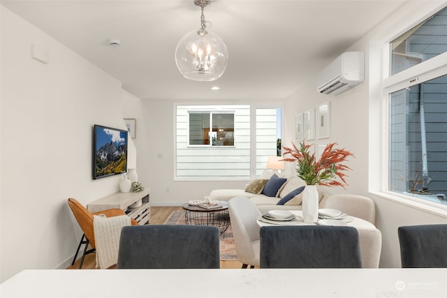 living room featuring hardwood / wood-style floors, a wall unit AC, and a chandelier