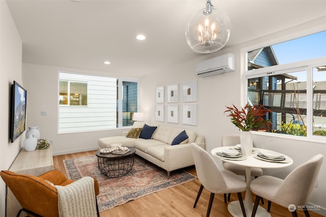 living room with a chandelier, a wall unit AC, and light hardwood / wood-style flooring