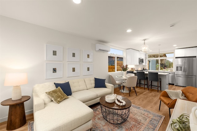 living room featuring a wall mounted air conditioner, plenty of natural light, and light hardwood / wood-style floors