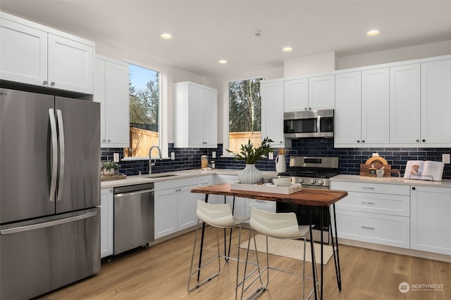 kitchen featuring sink, tasteful backsplash, light hardwood / wood-style floors, white cabinetry, and stainless steel appliances