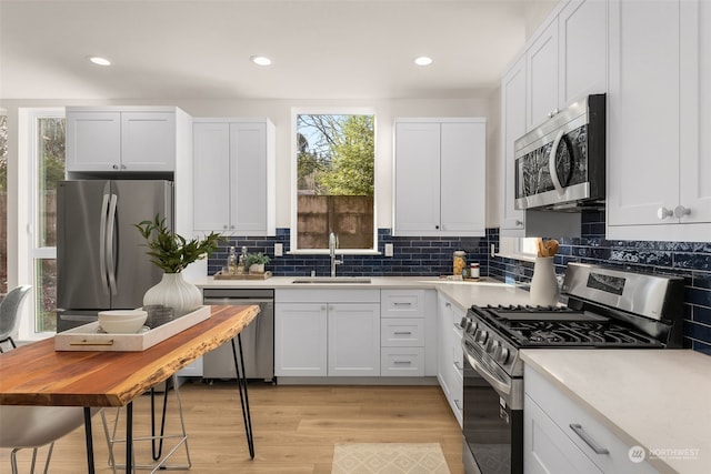 kitchen featuring white cabinetry, sink, stainless steel appliances, and light hardwood / wood-style flooring