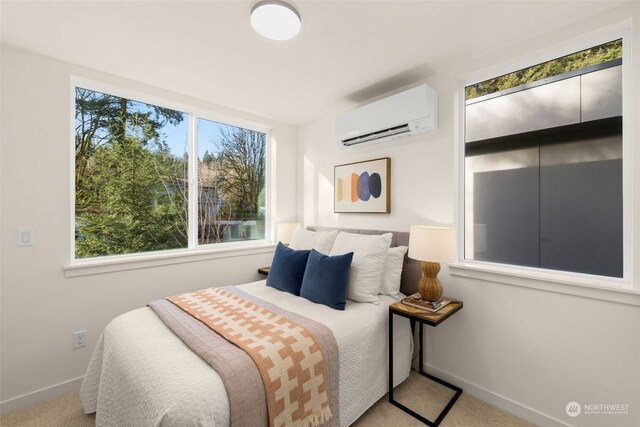 bedroom with a wall mounted air conditioner and light colored carpet