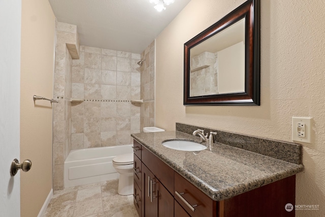 full bath featuring a textured wall, toilet, vanity, baseboards, and shower / washtub combination