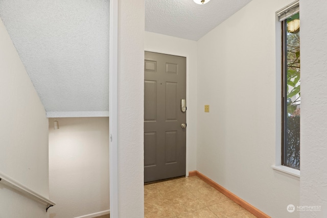 interior space with a textured ceiling and baseboards