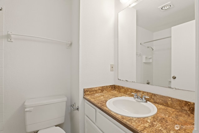 bathroom featuring vanity, toilet, and walk in shower