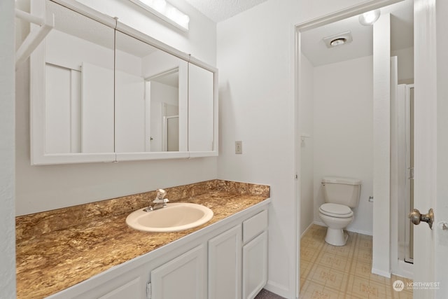 bathroom featuring baseboards, vanity, toilet, and tile patterned floors