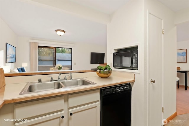 kitchen with black appliances, light countertops, a sink, and open floor plan