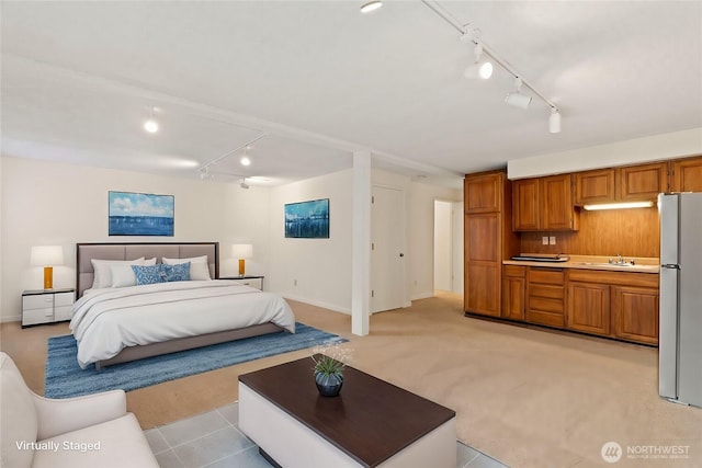 bedroom with a sink, light colored carpet, track lighting, and freestanding refrigerator