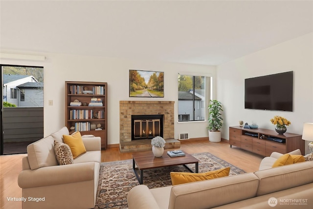 living area featuring light wood-type flooring, a fireplace, and visible vents