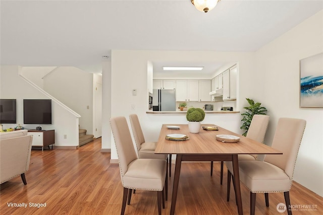 dining area featuring stairway, baseboards, and wood finished floors