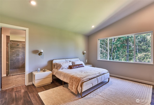 bedroom with connected bathroom, dark wood-type flooring, and vaulted ceiling