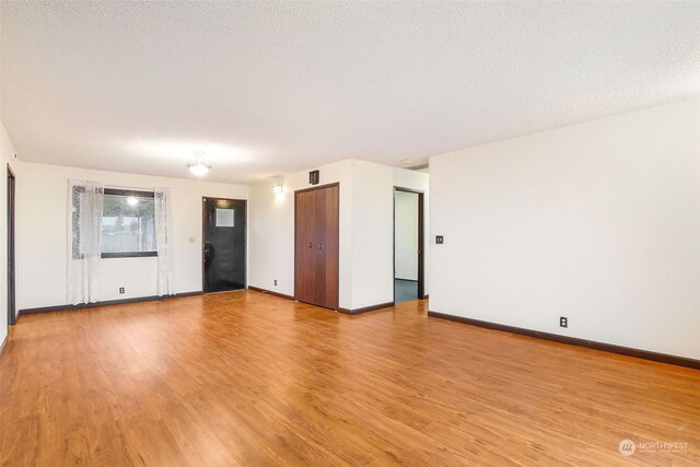 empty room featuring a textured ceiling and light hardwood / wood-style flooring