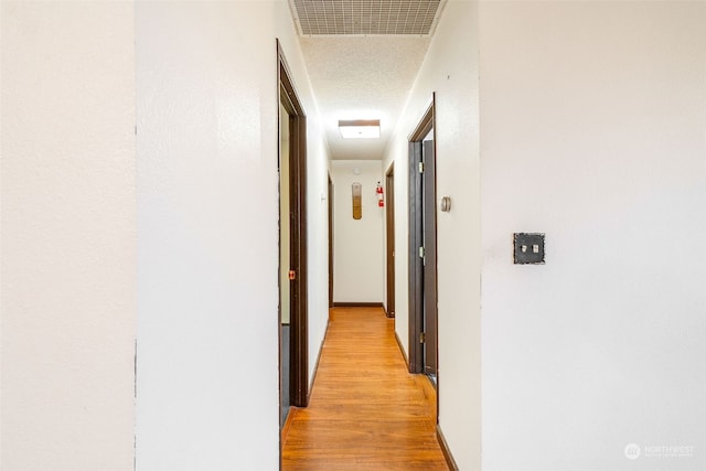 hall featuring light hardwood / wood-style floors and a textured ceiling