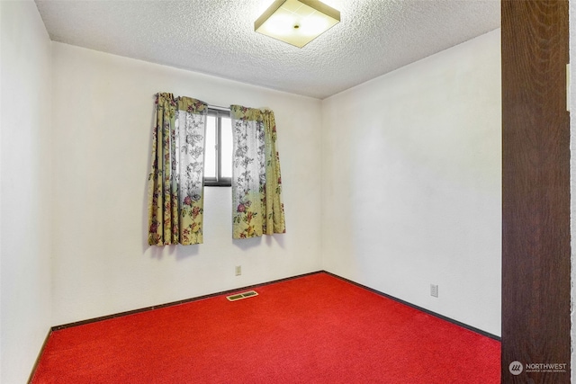 unfurnished room with a textured ceiling and carpet floors