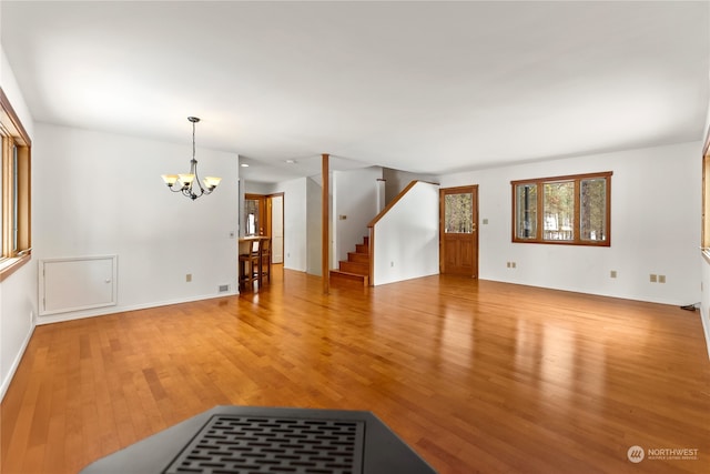 unfurnished living room with an inviting chandelier and hardwood / wood-style flooring