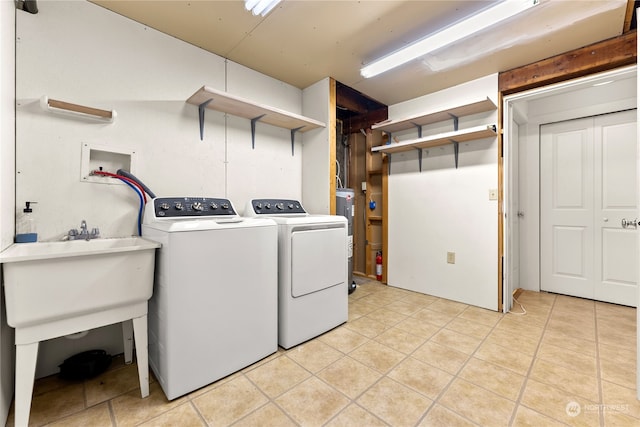 laundry area featuring water heater, separate washer and dryer, and light tile patterned floors