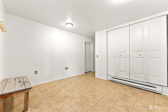 unfurnished bedroom featuring a baseboard heating unit, light tile patterned flooring, and a closet