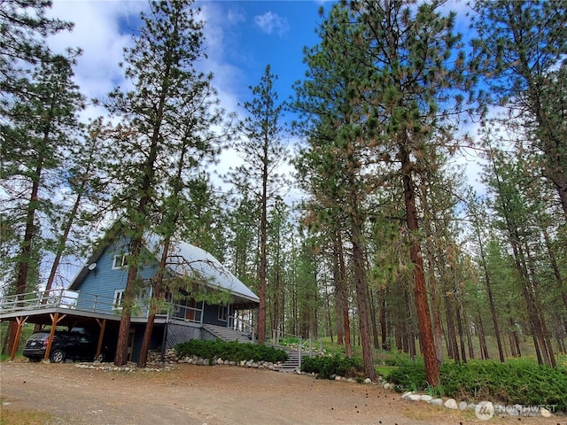 5 Chase Rd N, Winthrop, WA 98862 - view of property exterior featuring stairway, a carport, covered porch, dirt driveway, and a forest view