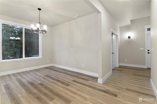 unfurnished room with light hardwood / wood-style floors and a notable chandelier