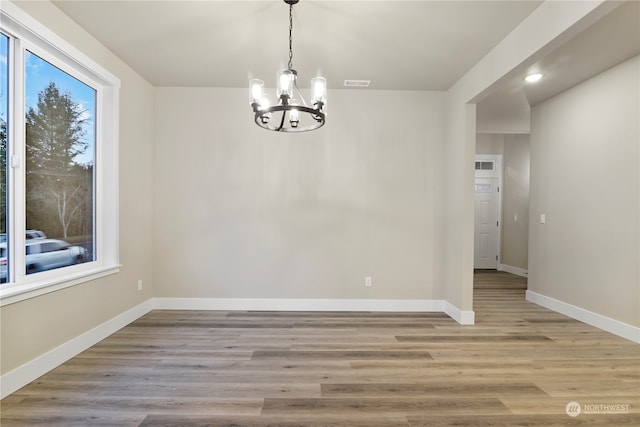 unfurnished dining area featuring plenty of natural light, light hardwood / wood-style flooring, and an inviting chandelier