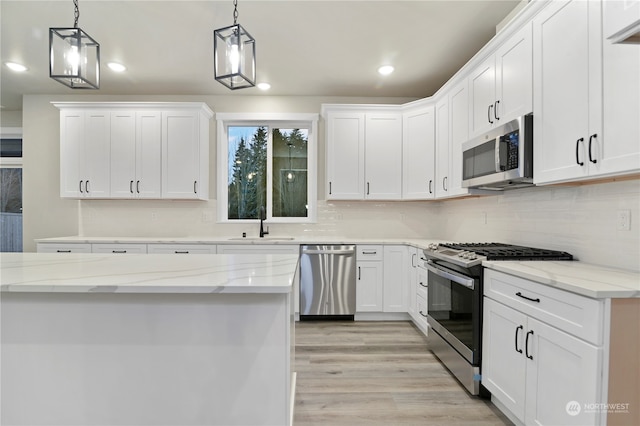 kitchen featuring white cabinets, decorative light fixtures, stainless steel appliances, and light stone counters