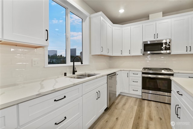 kitchen with white cabinets, light hardwood / wood-style floors, sink, and appliances with stainless steel finishes