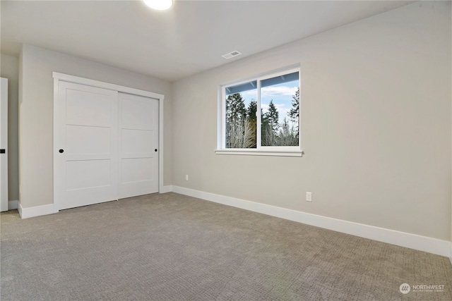 unfurnished bedroom with light carpet and a closet