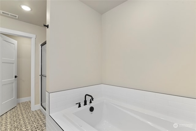 bathroom featuring tile patterned flooring and a relaxing tiled tub