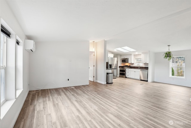 unfurnished living room with light hardwood / wood-style floors, an AC wall unit, and sink