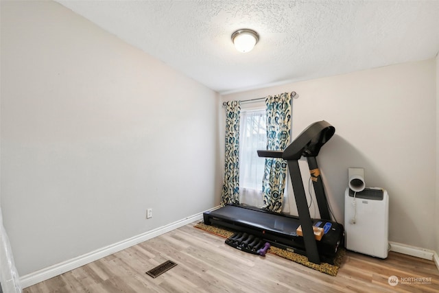 exercise area with wood-type flooring and a textured ceiling