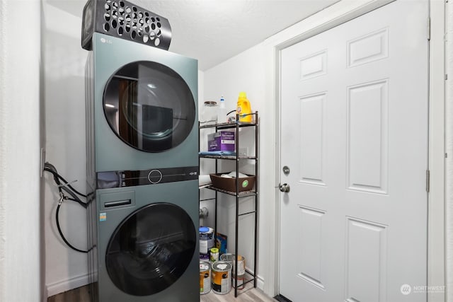 laundry room with a textured ceiling, wood-type flooring, and stacked washer and dryer