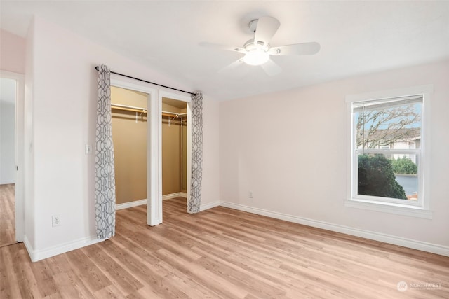 unfurnished bedroom with ceiling fan, two closets, and light hardwood / wood-style flooring