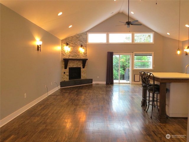 unfurnished living room with a fireplace, ceiling fan, dark wood-type flooring, and high vaulted ceiling